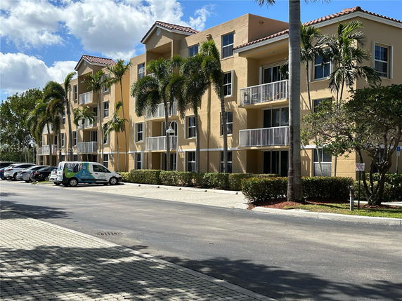 Front view of a four-story residential building with balconies and a tiled roof.