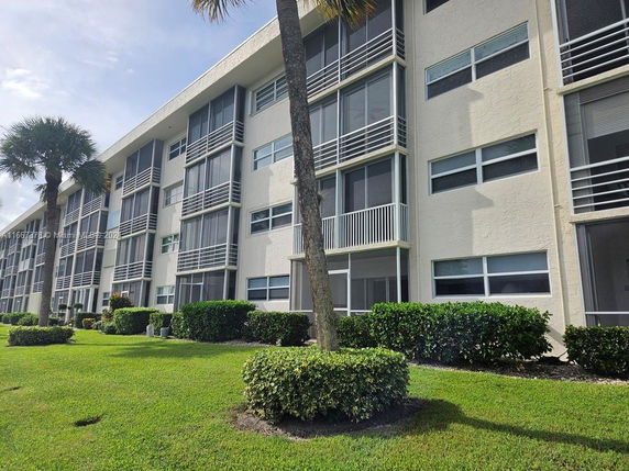 Front view of a multi-story residential building with balconies and large windows.