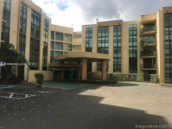 Front view of a multi-story building with large windows and an entrance canopy.
