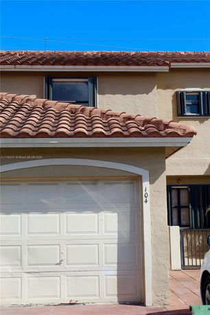 Front view of a house with a garage and tiled roof.