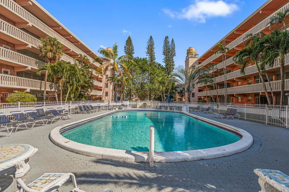 Outdoor view of a multi-story building with balconies surrounding a central swimming pool area.