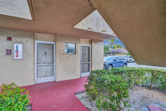 Front entrance view of a building with metal security doors and small windows.