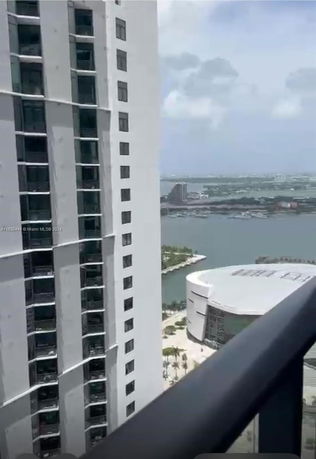 Panoramic view of a high-rise building and waterfront seen from a balcony.