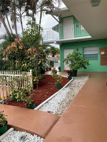 Front view of a two-story building with green walls and white railings.