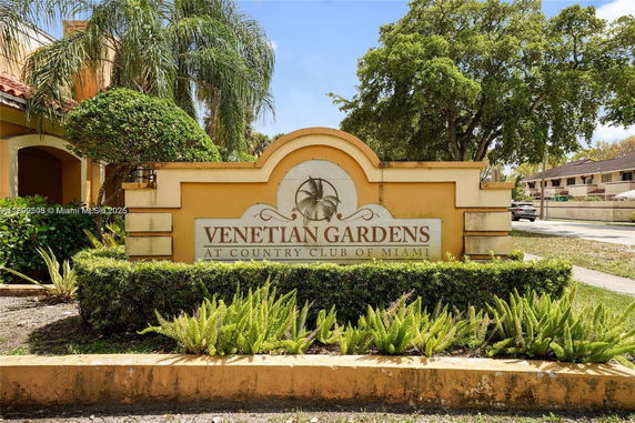 Entrance sign of Venetian Gardens with surrounding foliage.