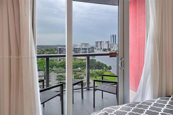 Panoramic view from a balcony overlooking distant buildings and green areas.