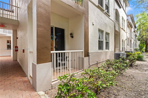 Front view of a multi-story building with a small patio area and railing.