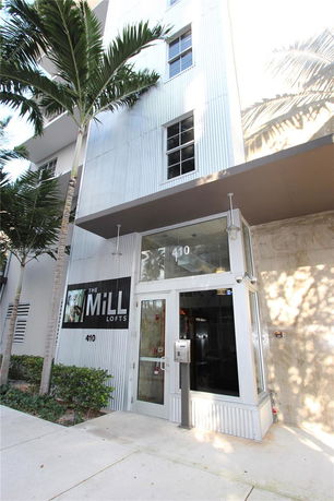 Front view of a modern loft-style building with metal siding and large windows.
