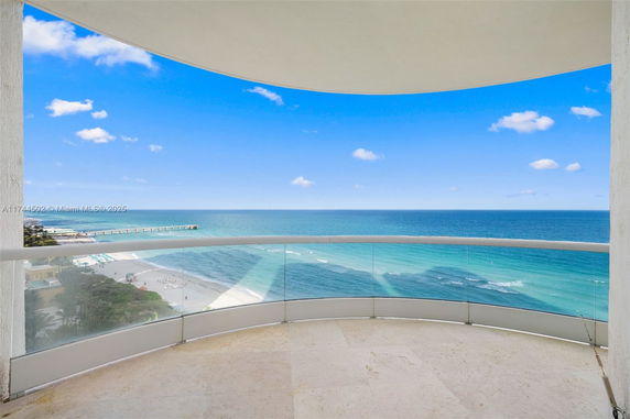 Panoramic view of the ocean from a balcony with a glass railing.