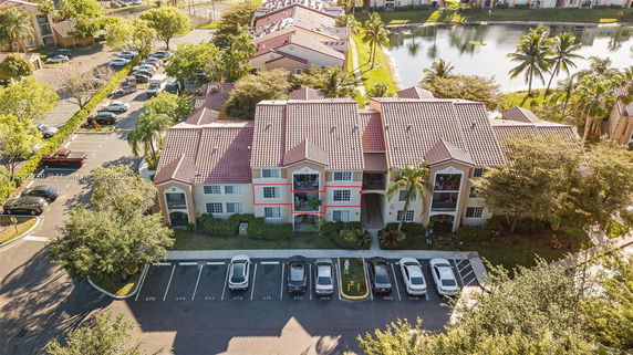 Front view of a multi-story residential building with tiled roofs and parking spaces.