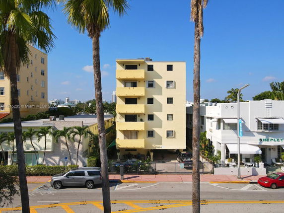 Front view of a multi-story yellow building with balconies and a gated entrance.