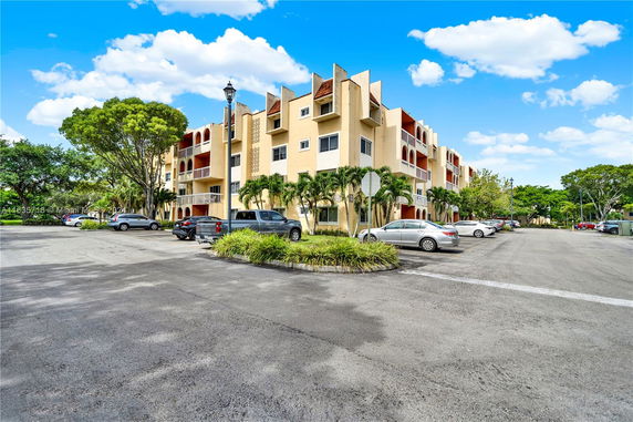 Front view of a multi-story residential building with parking area.