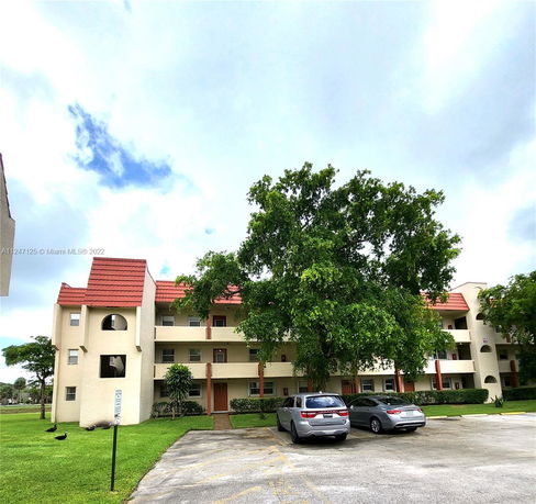 Front view of a multi-story residential building with a red roof and beige exterior.