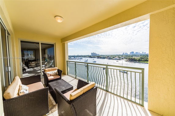 Balcony with chairs and a panoramic view of water and distant buildings.