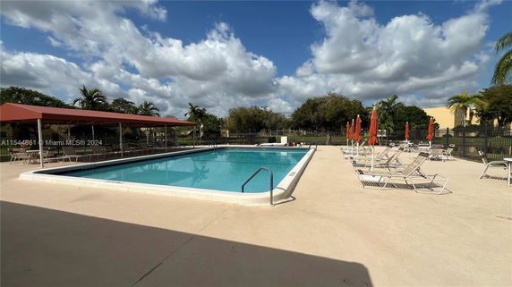 Outdoor swimming pool area with lounge chairs and umbrellas.