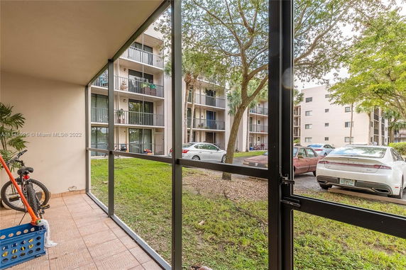 View of a parking area and apartment buildings from a screened patio.