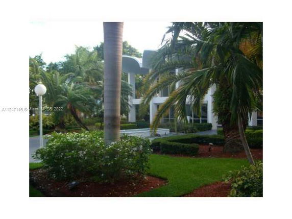 Front view of a modern two-story house surrounded by palm trees.