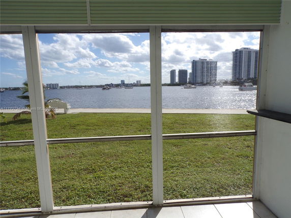 View of surrounding areas seen through a window, featuring water and tall buildings.