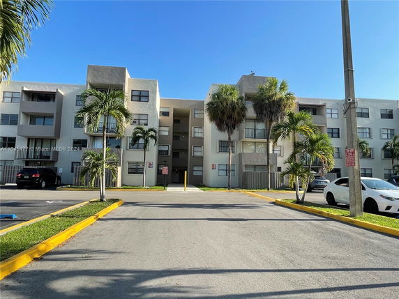 Front view of a multi-story residential building with a parking area.