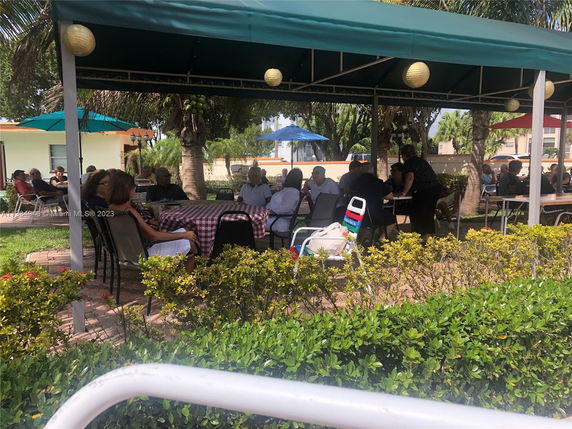 Outdoor seating area with people sitting under a canopy.
