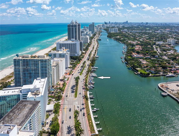 Panoramic view of a coastal cityscape with high-rise buildings along a beach and a river.