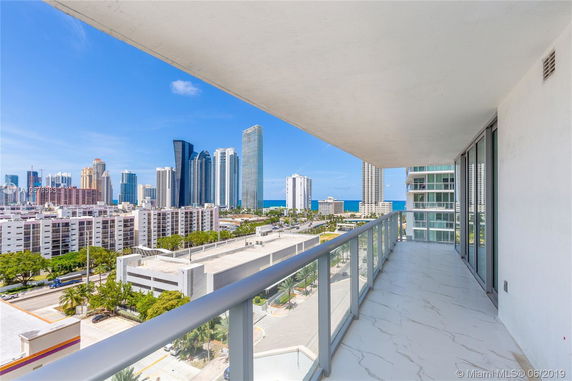 Balcony with a view of high-rise buildings and the ocean in the distance.