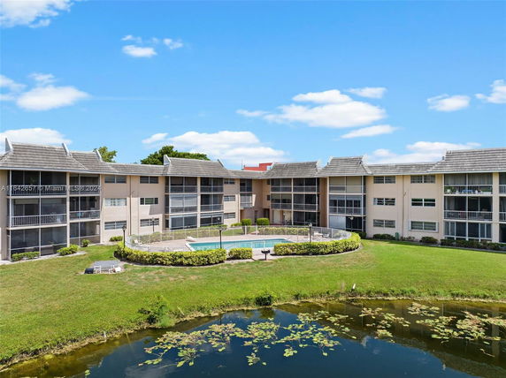 Front view of a multi-story residential building with screened balconies and a swimming pool.
