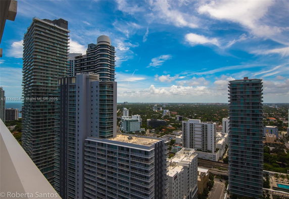 View of high-rise buildings in an urban area under a blue sky with scattered clouds.