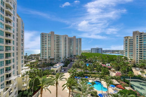 View of multiple high-rise residential buildings with swimming pools and greenery in the foreground.