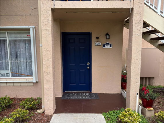 Front view of a house entrance with a blue door and potted plants.