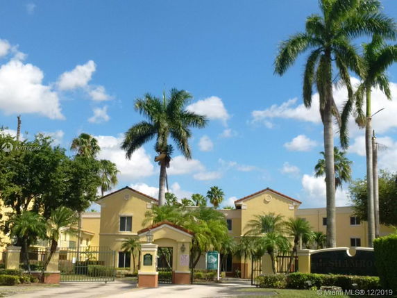 Front view of a multi-story residential building with a gated entrance.