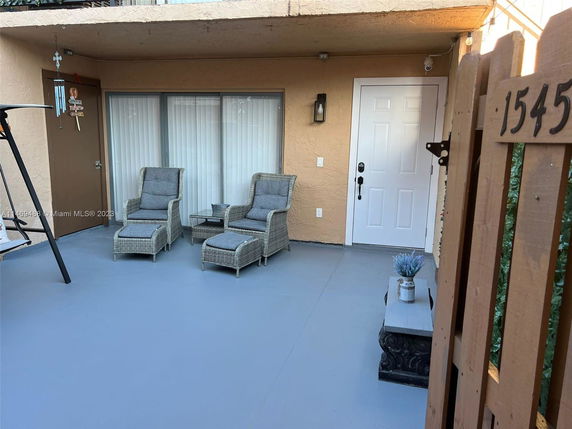 Front view of a patio area with a white door and two outdoor chairs and a table.