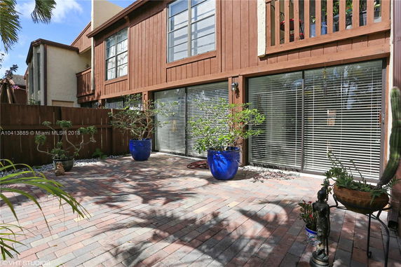 Front view of a two-story wooden house with large windows and a brick patio.