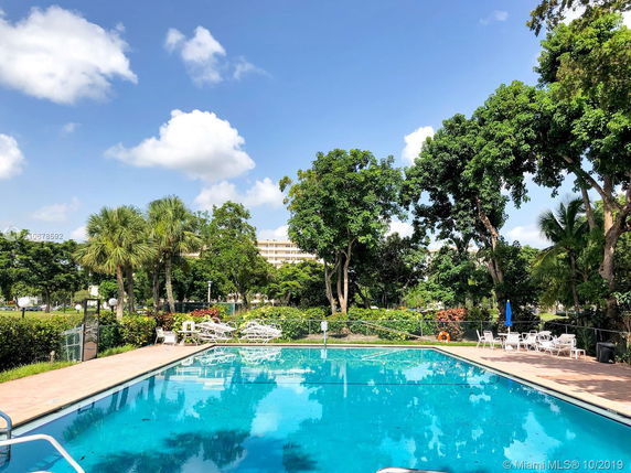 Outdoor swimming pool area with surrounding greenery and seating.