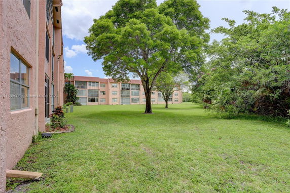 Rear view of multiple apartment buildings with trees and grassy area