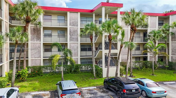 Front view of a multi-story apartment building with balconies and red roof accents.