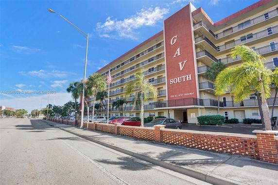 Front view of a multi-story building with balconies and a red vertical facade.