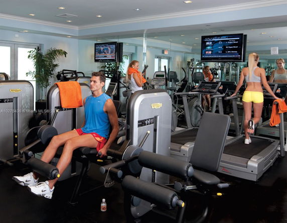 Interior view of a gym with various exercise equipment and people working out.