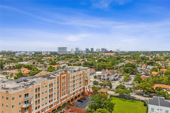 Aerial view of a multi-story building with a cityscape and greenery in the background.