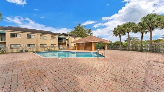 Outdoor swimming pool area with a building in the background.