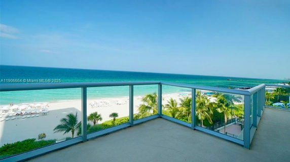 Panoramic view of the ocean from a balcony with glass railing.