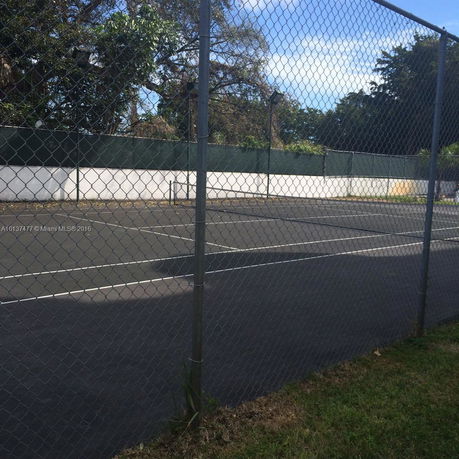 Tennis court with surrounding fence and trees.