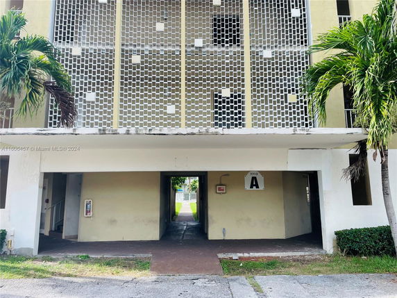 Front view of a multi-story building with a grid-like facade and an open ground-level entrance.