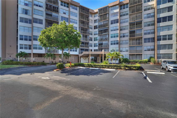 Front view of a multi-story residential building with a parking area.