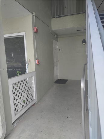 Exterior view of an apartment entrance with railing and door.