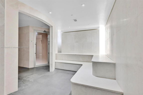 Interior view of a steam or sauna room with tiled benches and walls.