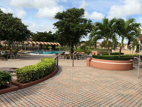 Outdoor area with a swimming pool surrounded by trees and seating.