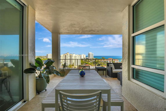 Balcony view with outdoor furniture overlooking a scenic vista of buildings and the ocean.