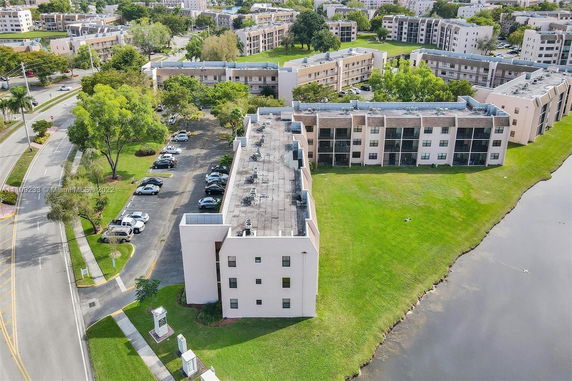 Aerial view of residential apartment building with parking area and green spaces.