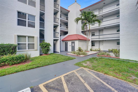 Exterior view of a multi-story residential building with balconies and green landscaping.
